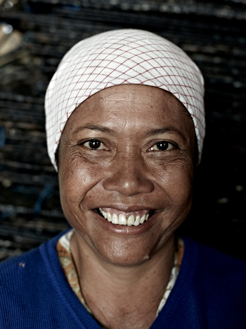 Woman's portrait smiling to the camera with a white scarf over hair.