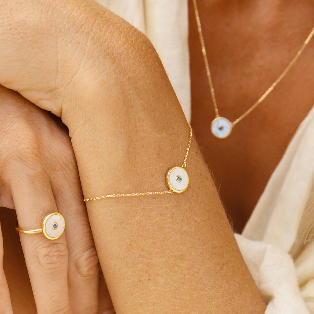 Woman wearing a set of mother of pearl necklace, bracelet and ring, very close crop.
