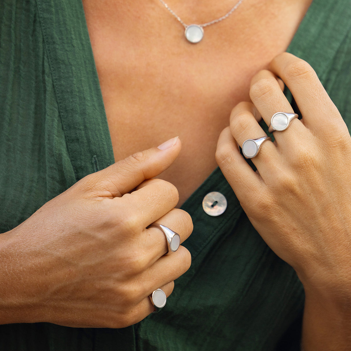 Woman moelling silver jewellery with a green top close crop no background visible.