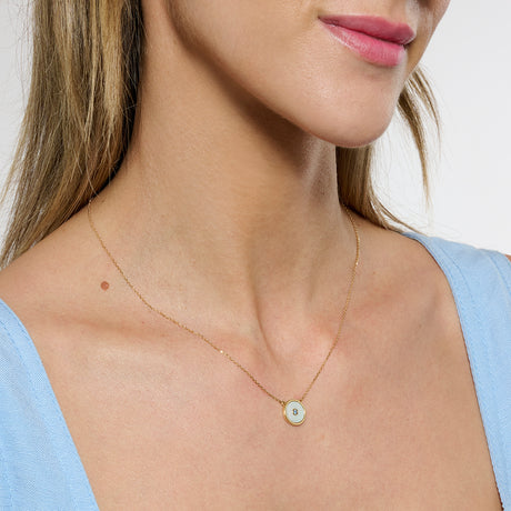 Model close cropped to the chin, wearing gold mother of pearl necklace