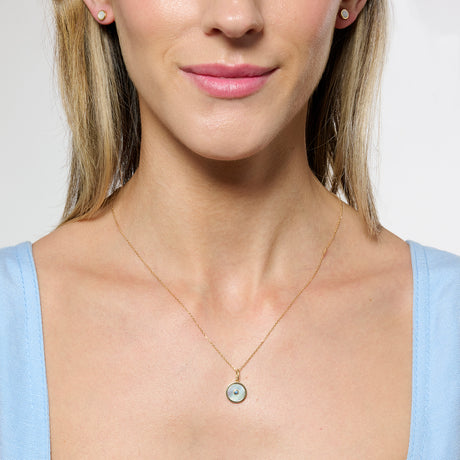 Model close cropped to the chin wearing gold mother of pearl necklace