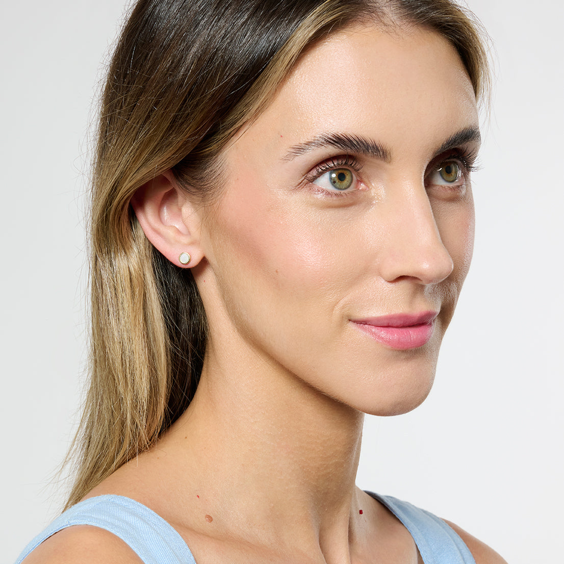 Model facing side on to the camera wearing gold mother of pearl studs