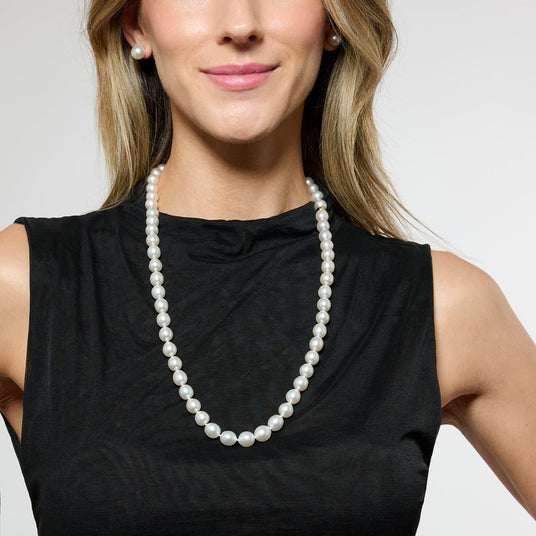 Woman wearing a long pearl necklace against a plain background