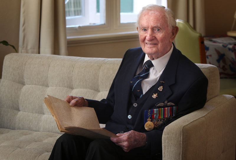 Veteran sitting on couch with his prisoner of war diary.