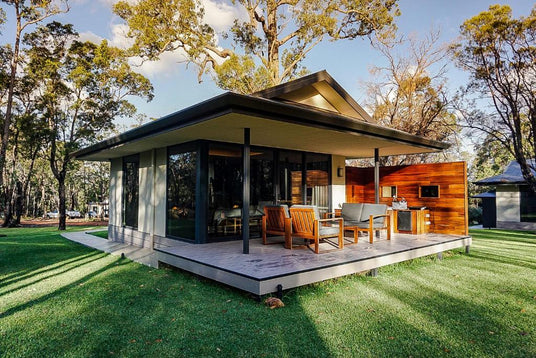 Modern house with a deck and outdoor furniture in a green, tree-lined area