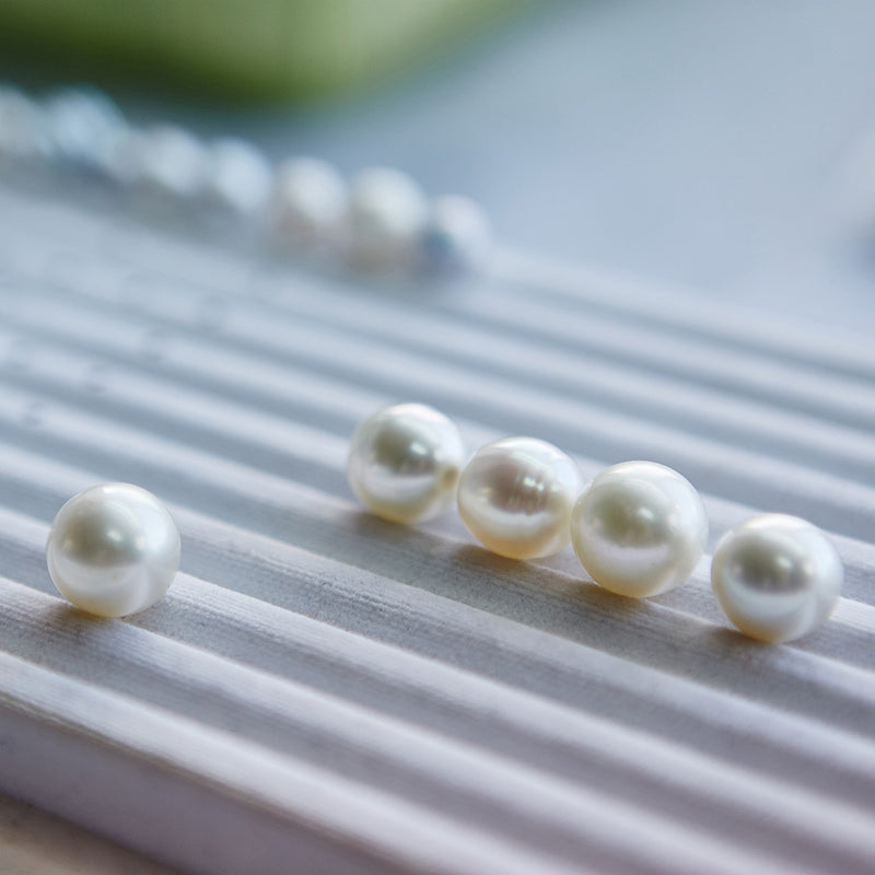 Loose pearls lined up on a textured surface with a blurred background