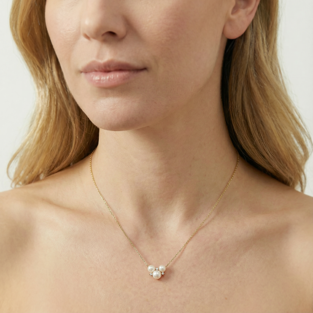 Close-up of a woman wearing a delicate gold necklace with a small pendant.