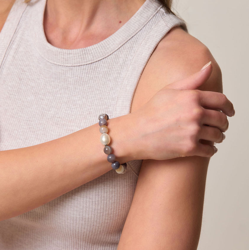 Person wearing a beaded bracelet on a neutral background