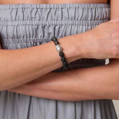 Person wearing a bracelet with beads on an arm crossed over the chest.