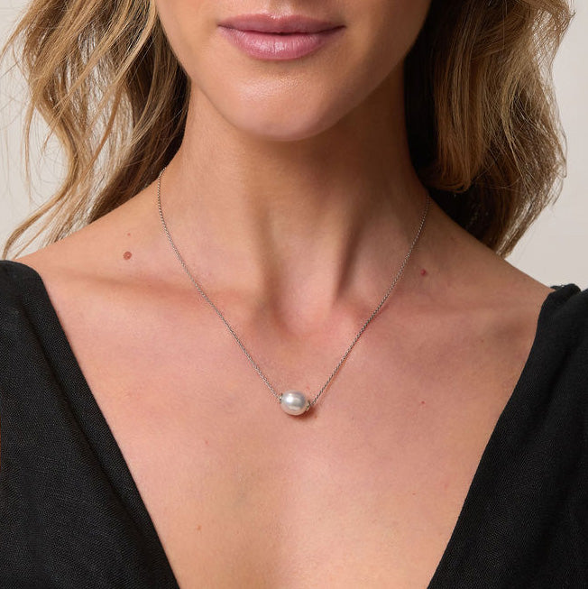 Pearl necklace worn by a person with a neutral background