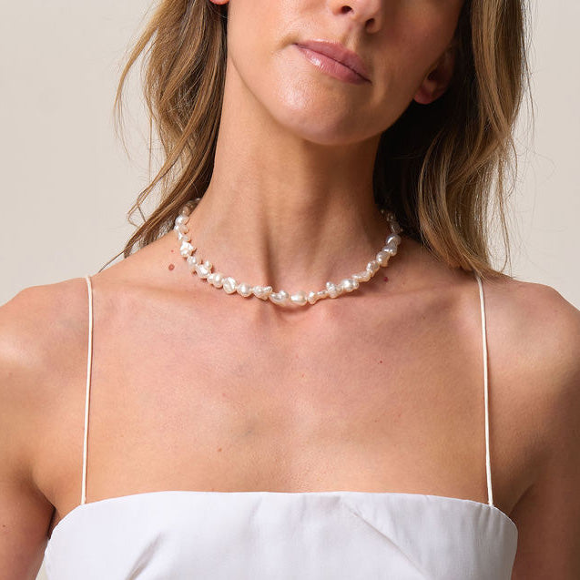 Woman wearing a pearl necklace against a neutral background