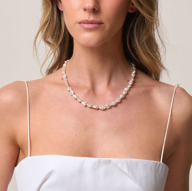 Woman wearing a pearl necklace with a plain background
