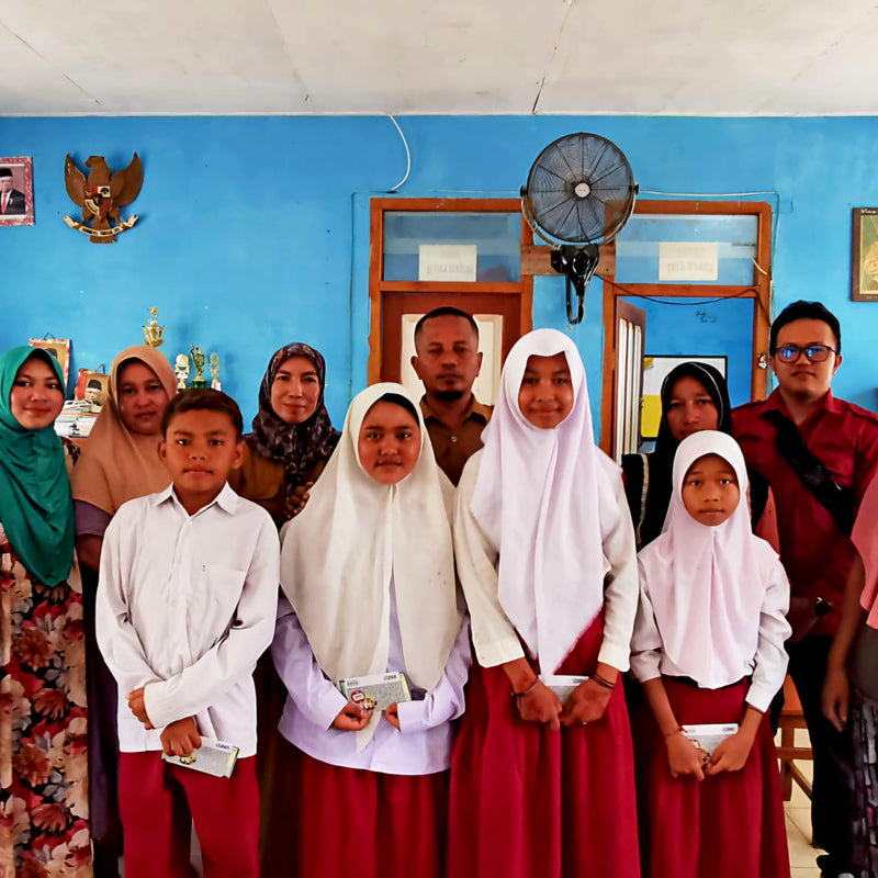 Group of people, including children and adults, posing for a photo in a room with blue walls and a fan.