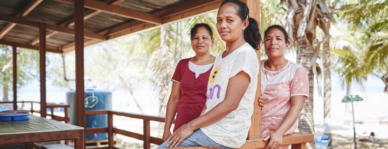 three women sitting on a wooden balcony