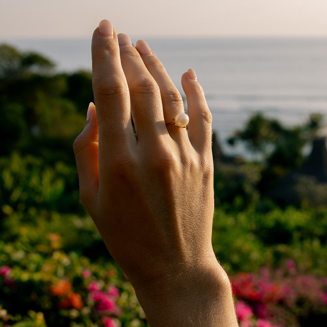 Hand with a ring on a blurred natural background