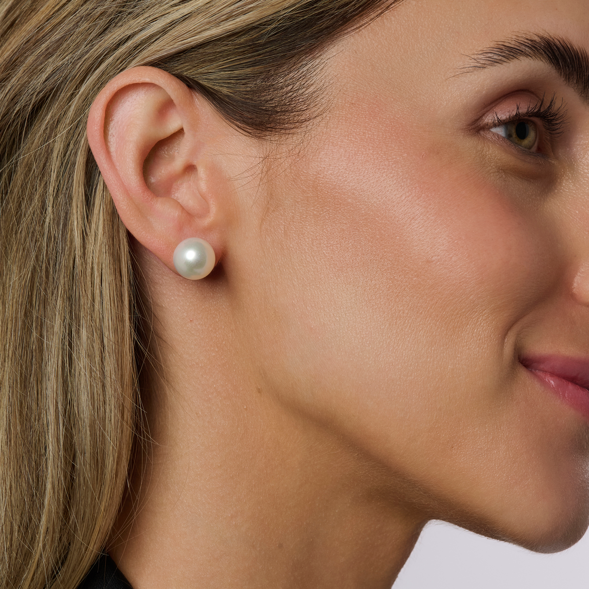 On model Flat Button (BF) pearls have a round appearance from the front but are flatter and more button-shaped. They are a popular and widely available shape. These earrings come in sizes ranging from 9mm to 12mm and are set in 18K yellow gold. Available in various sizes, the BF pearls are a timeless choice, offering a unique yet classic look.