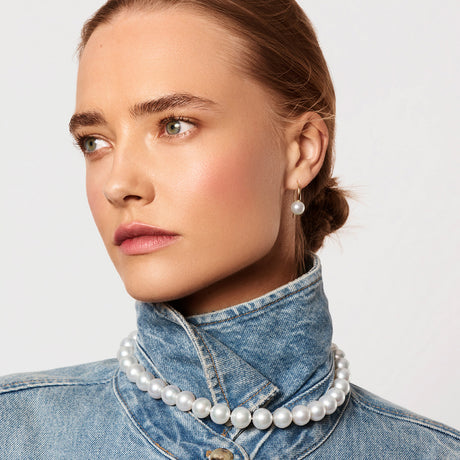 Woman wearing a pearl necklace and earrings against a light background