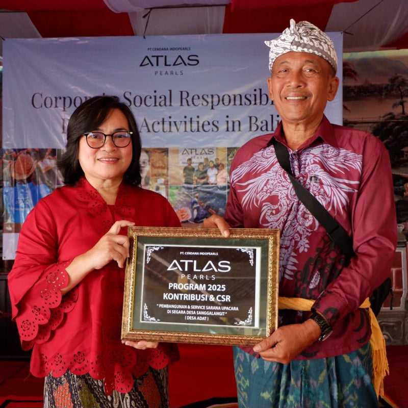 Two people holding an Atlas Pearls plaque in front of a branded backdrop