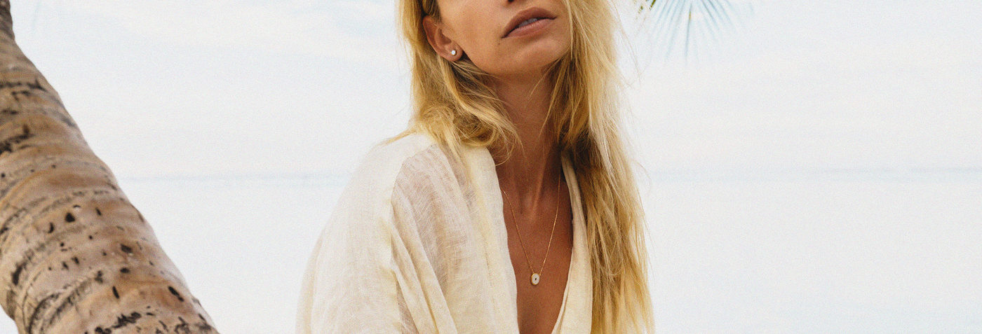 Woman with long blonde hair wearing a white top against a light background