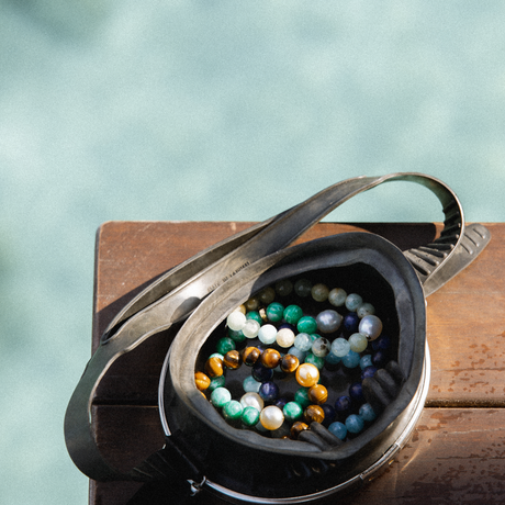 multicolored bead bracelets inside snorkle mask on a wooden surface