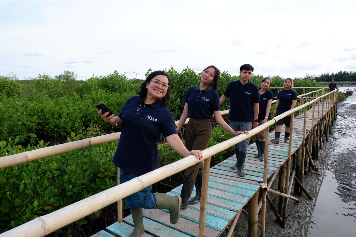 Group of people walking on a wooden boardwalk in a natural setting