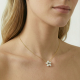 Gold necklace with a floral pendant worn by a person