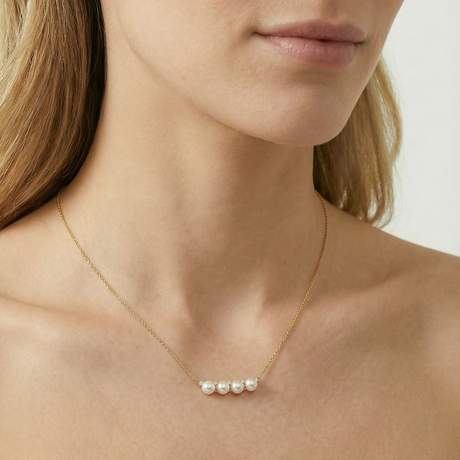 Pearl necklace on a person with a neutral background