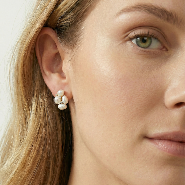 Close-up of a woman wearing pearl earrings with a neutral background