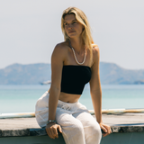 Woman sitting on a dock by the water with mountains in the background