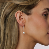 On model The Modern Hook Earring in 925 Sterling Silver features 8mm South Sea pearls in a round shape (NL2). The earrings have a white colour and are graded C, with a total dimension of 3.5 cm.