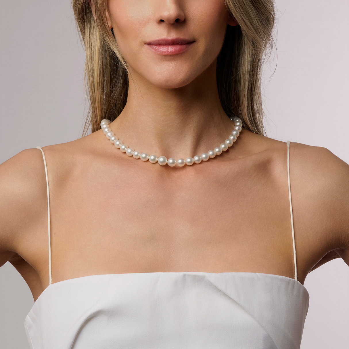 On Model Circle South Sea pearl strand with 40 white pearls (10.8 x 10mm), hand-selected for size, shape, lustre, and colour. This 42cm strand is finished with a 925 silver Nittle clasp and rondel, showcasing the natural beauty of sustainably sourced pearls from Atlas Pearls.