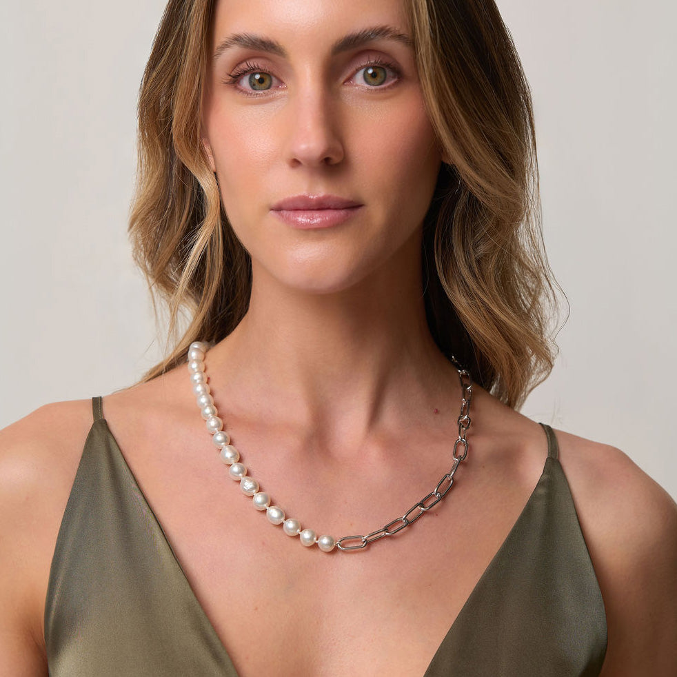 Woman wearing a pearl and chain necklace against a neutral background