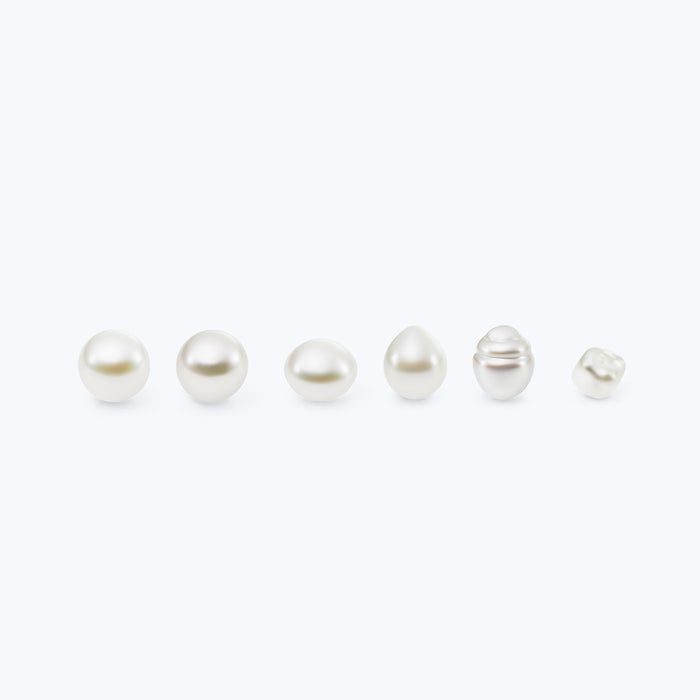Set of six pearls of varying sizes and shapes on a white background