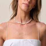 Woman wearing a pearl necklace against a neutral background