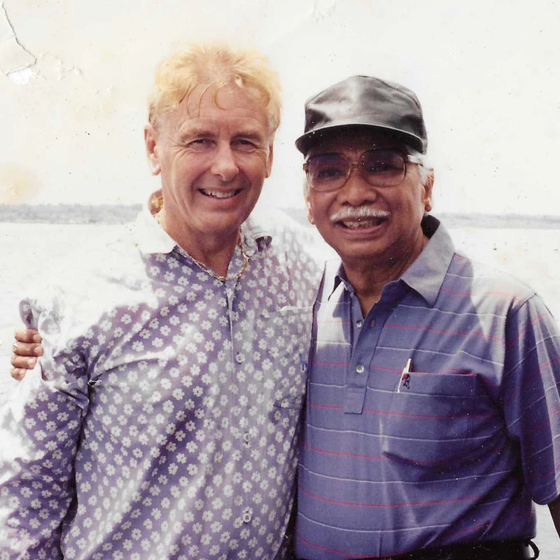 Two men embracing with ocean behind them. 