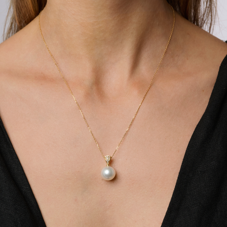 On model This pendant features a delicate 18K yellow gold design with pavé-set diamonds surrounding an 11mm South Sea semi-round pearl. The pearl has a B2 grade and white color. Available in 18K white, yellow, and rose gold, this piece has a total height of 20mm. Chains are sold separately.