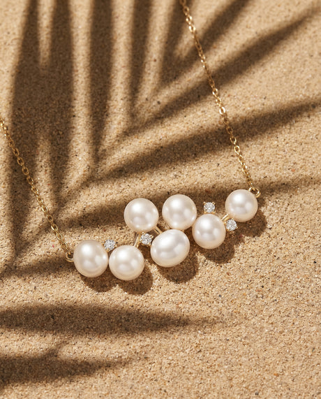 Necklace laying in sand with palm leaf casting shadow over top