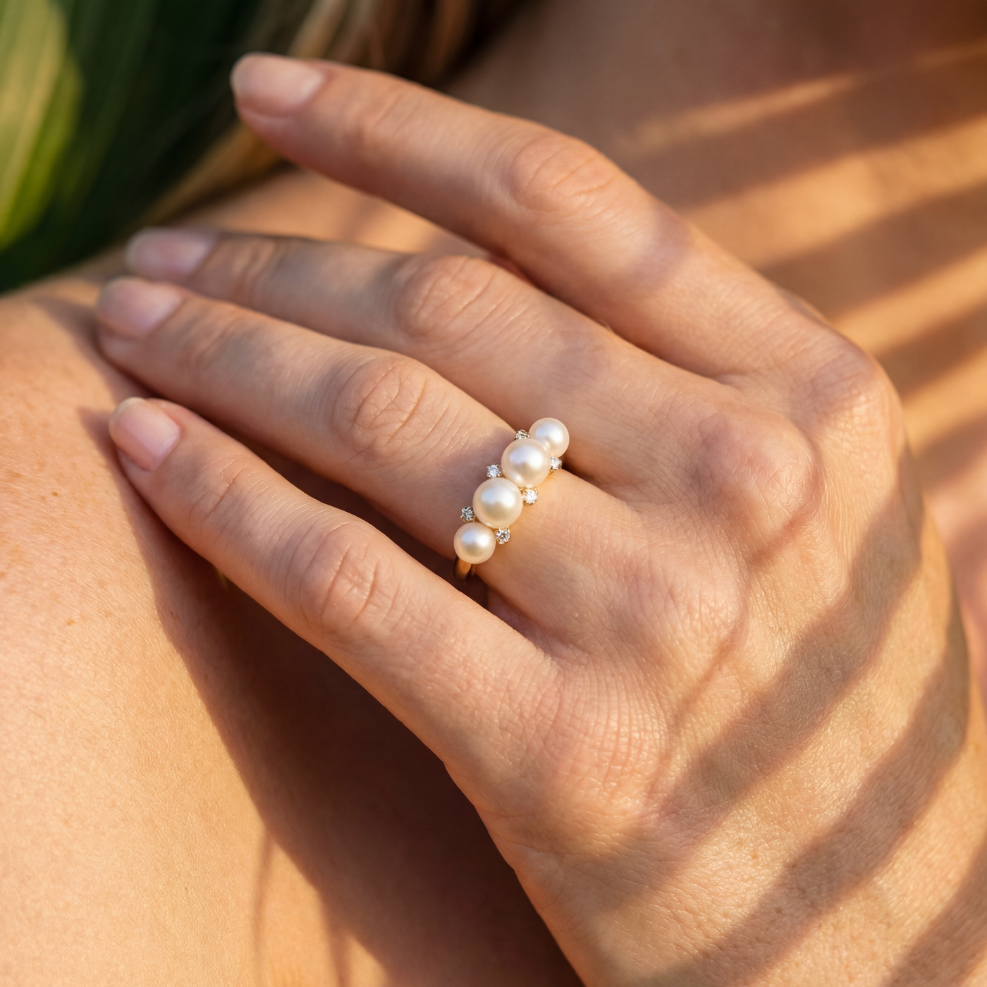Hand wearing a pearl ring with sunlight casting shadows