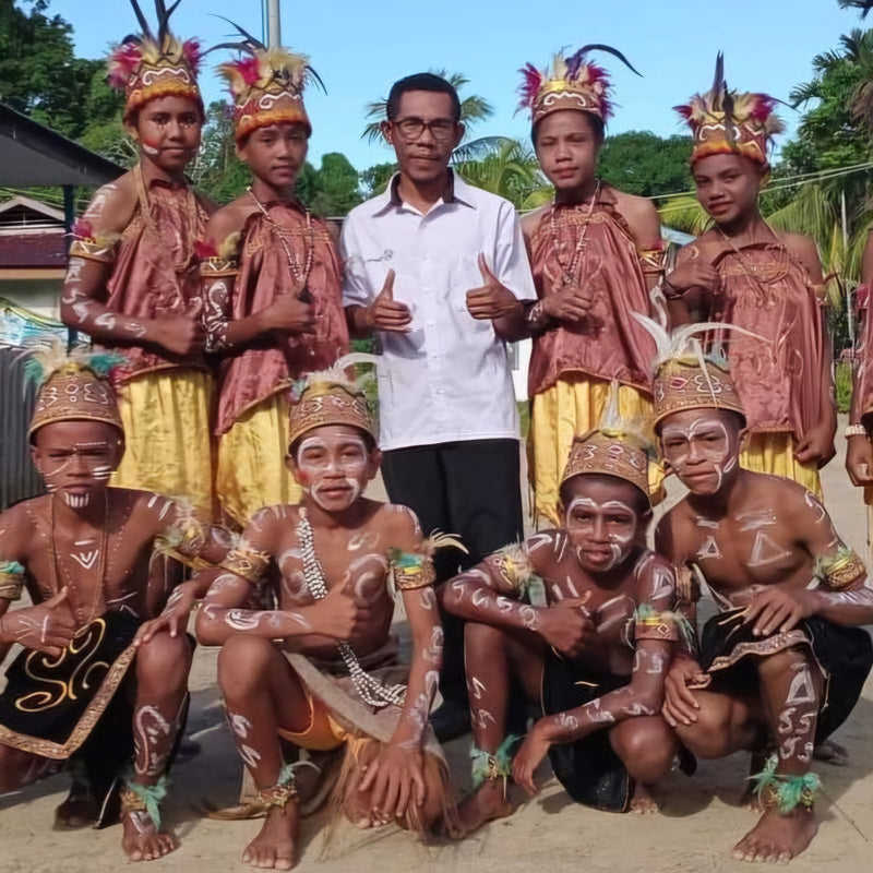 Group of people in traditional attire with a person in modern clothing giving a thumbs-up.